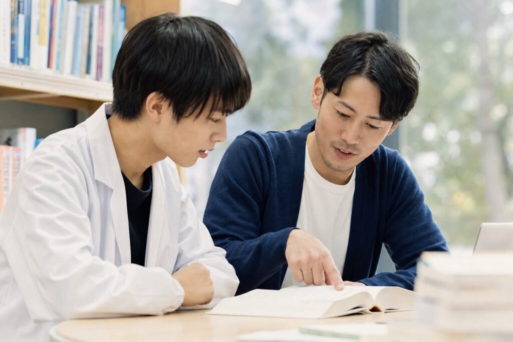 男子学生と家庭教師が進級のコツを話し合う様子